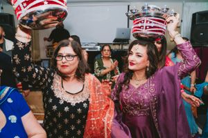 Party guests in traditional attire lifting decorative crowns during a celebration.