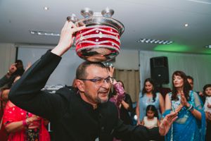 Person raising a decorative crown while others clap during a celebration.