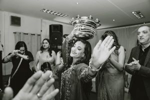 Black and white photo of people celebrating with raised hands at an indoor party.