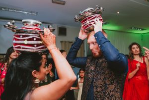 Guests participate in traditional pot-balancing dance at indoor celebration.
