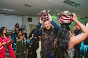 Guests balance decorated pots during lively indoor celebration.