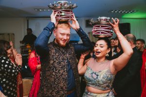 Couple raising decorative crowns while dancing at a celebration party.