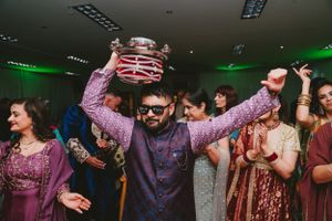 Guest wearing sunglasses celebrates with decorated pot at indoor party.