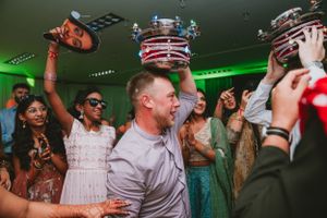 Energetic party scene with people dancing and raising striped ceremonial poles in celebration.