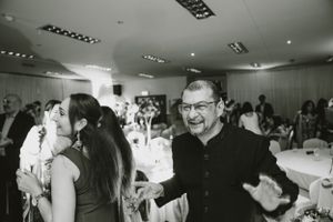 Guests dance and socialize at an indoor party with white tablecloths and ambient lighting.