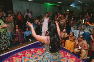 Dancers celebrate on a vibrant patterned dance floor at an indoor party with festive lighting.