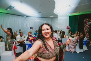 Party guests dance and celebrate on a dance floor with green ambient lighting at an indoor event.