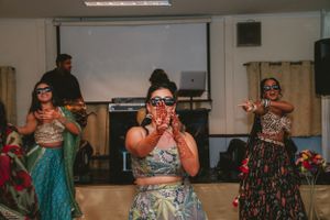 Dancers in ornate outfits performing expressive movements during an indoor event.