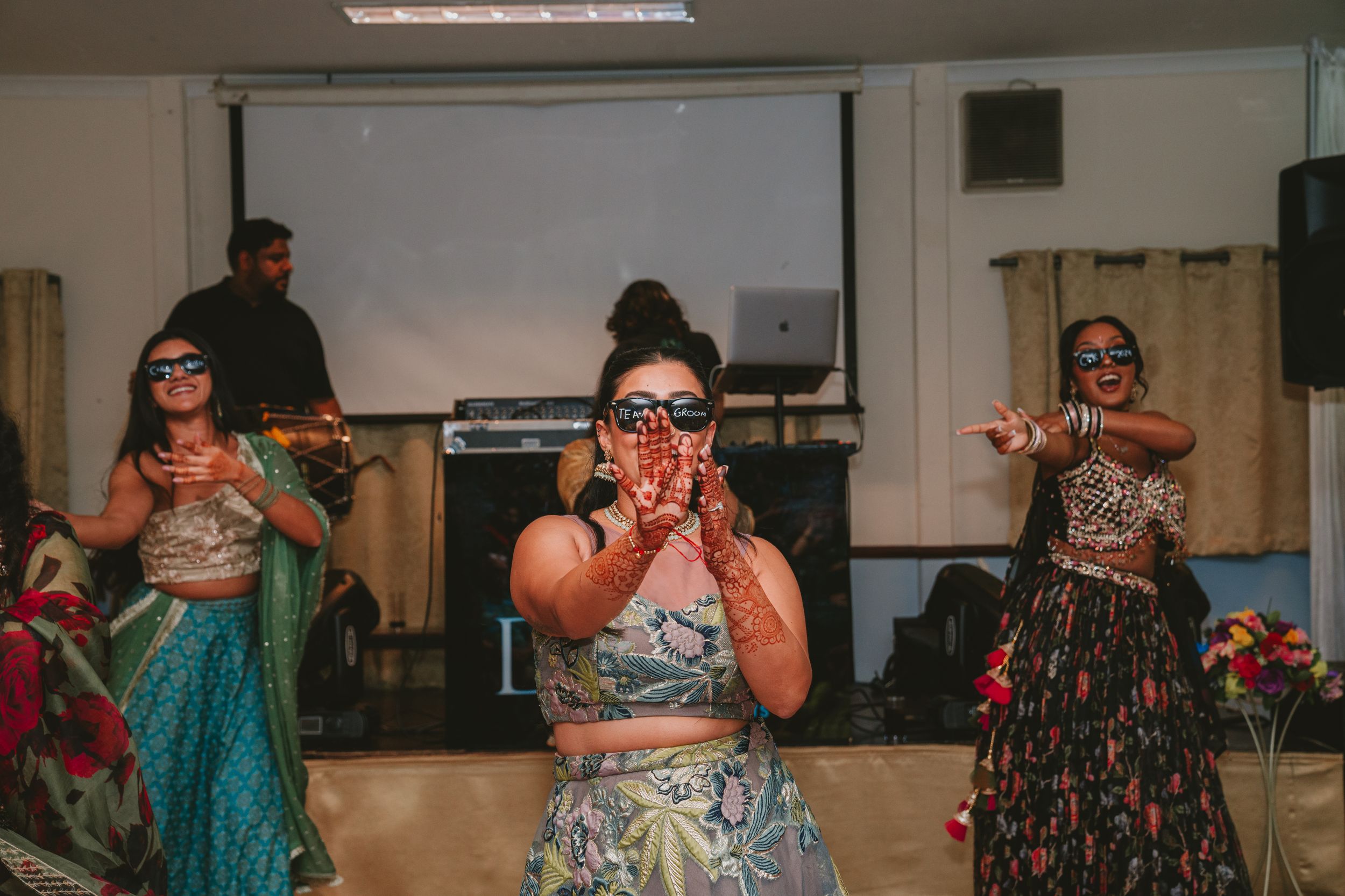 Performers in traditional attire dancing during an indoor cultural celebration.