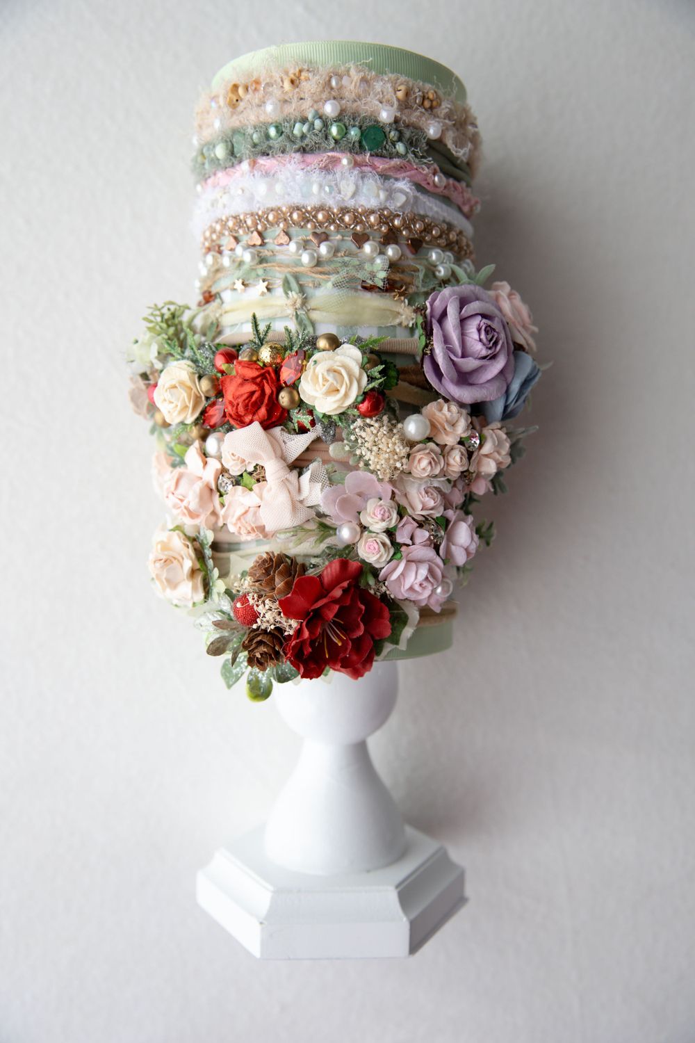 Collection of elegant floral baby headbands stacked on white display stand.