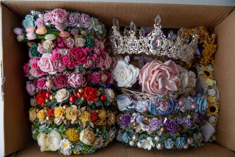 Cardboard box filled with colorful floral headbands and an ornate rhinestone crown tiara.