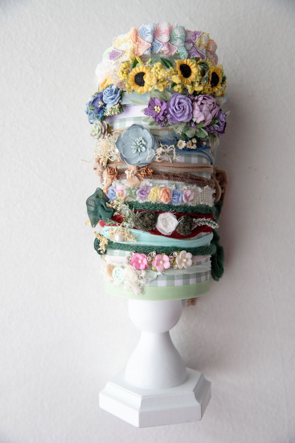 Stack of colorful floral baby headbands displayed on white pedestal stand.