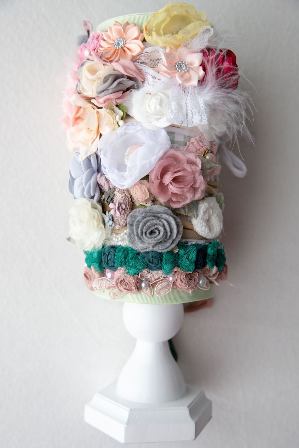 Collection of mixed floral and fabric baby headbands on white display stand.
