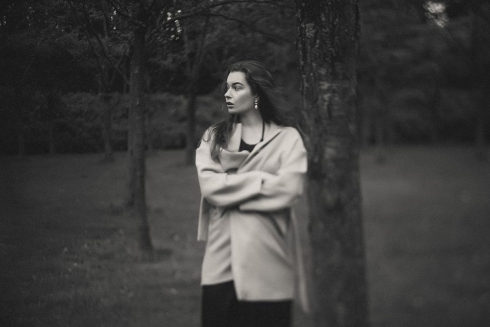 Atmospheric black and white portrait with soft focus and natural outdoor setting.
