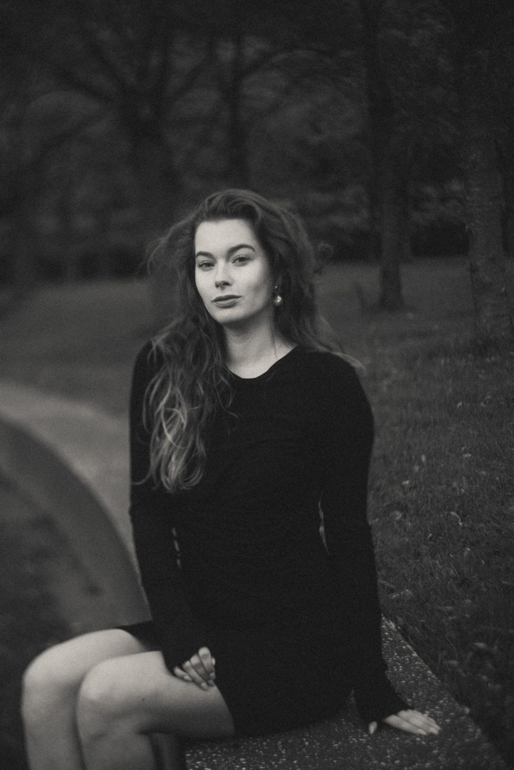 Vintage-style black and white portrait on grass with moody lighting.