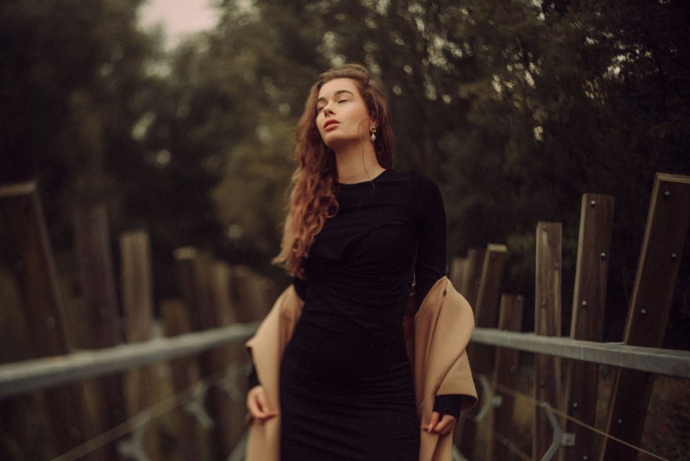 Dramatic outdoor portrait against trees with soft natural lighting.