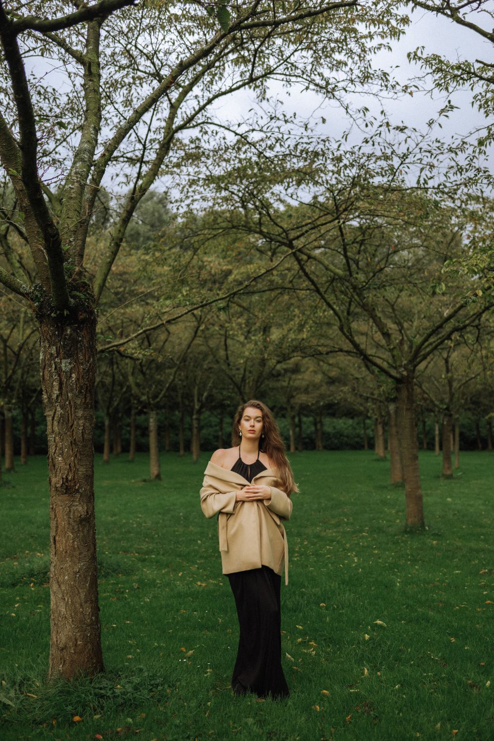 Artistic portraits in an orchard with scattered trees on green grass.