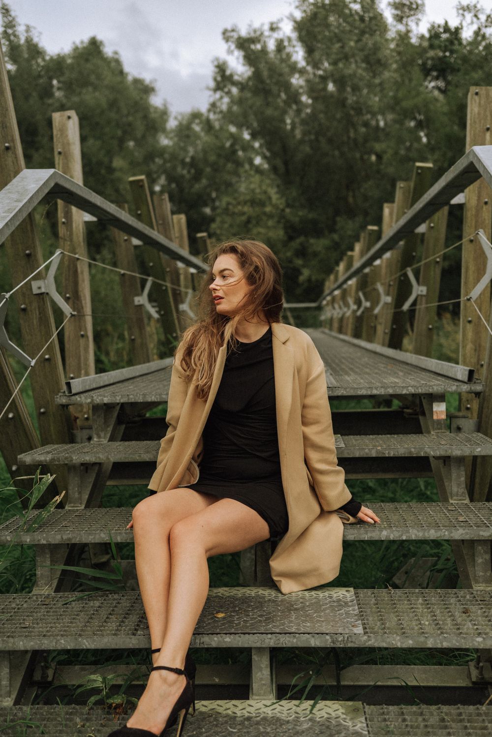 Fashion photography on wooden boardwalk steps surrounded by greenery.