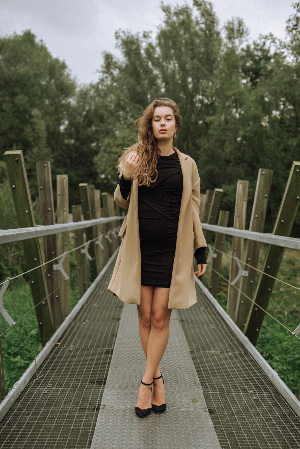 Fashion shoot on an industrial metal walkway surrounded by trees.