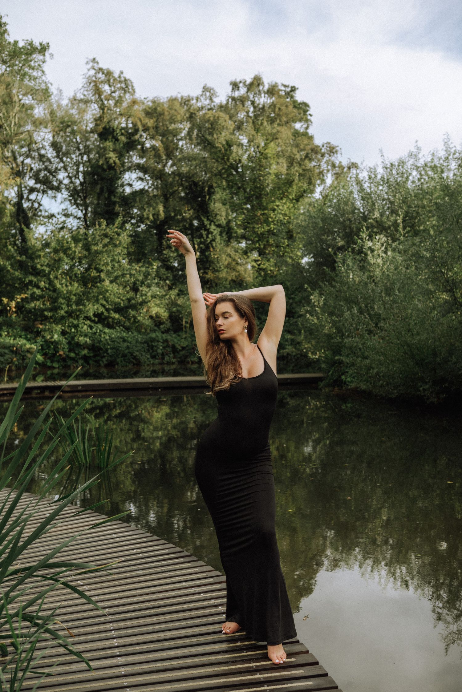Artistic sequence of poses on a wooden dock overlooking a tranquil pond surrounded by trees.