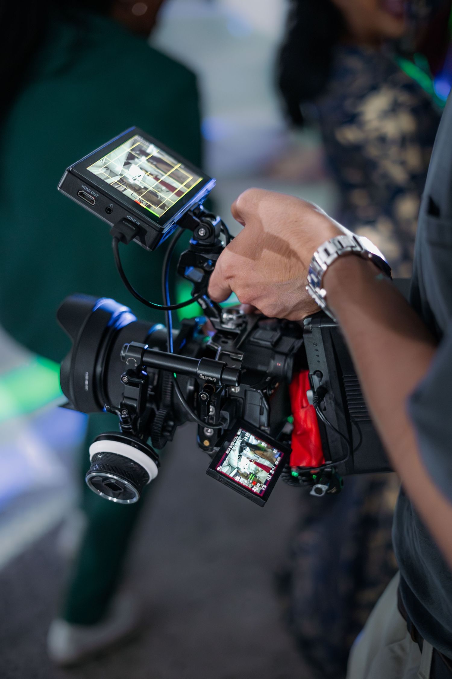 Close-up of cameraman operating professional video camera rig with external monitor.