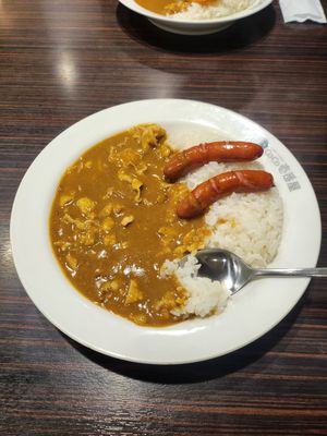 Japanese curry rice with sausage served on white plates shown in sequential photos on a dark wooden table.