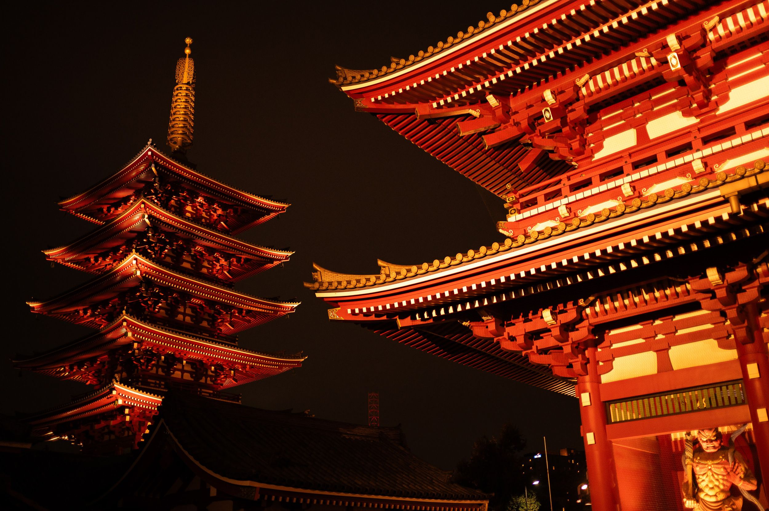 Illuminated red pagoda temple at Sensoji shrine in Asakusa, Tokyo glows against the dark night sky.