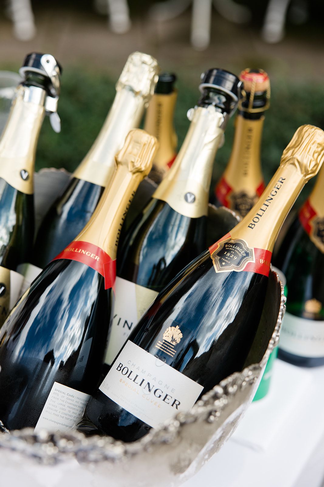 Chilled champagne bottles nestled in ice at an elegant event display with Bollinger and other luxury brands visible.
