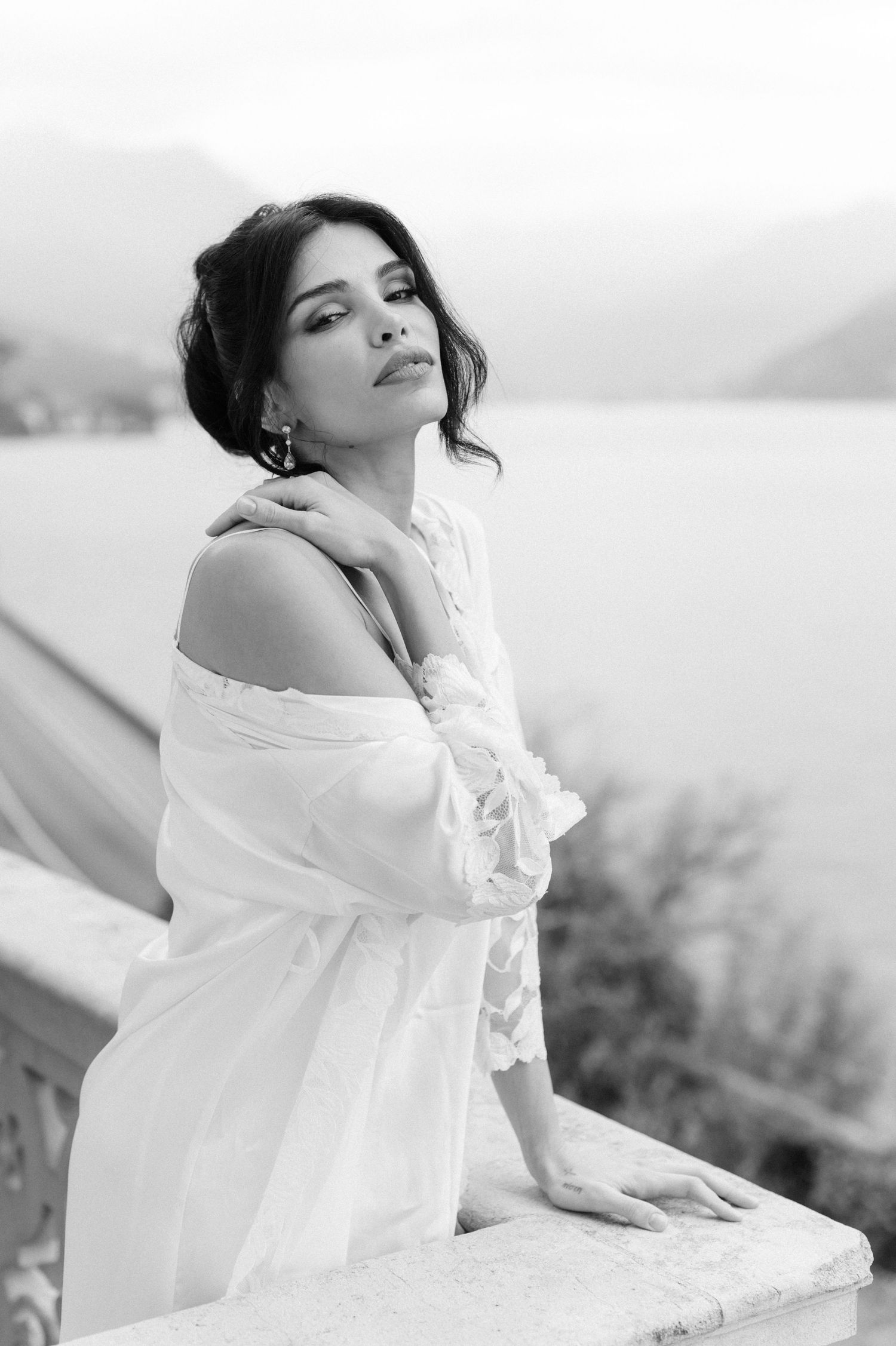 A series of black and white photos showing a person in a flowing white dress reclining gracefully outdoors.