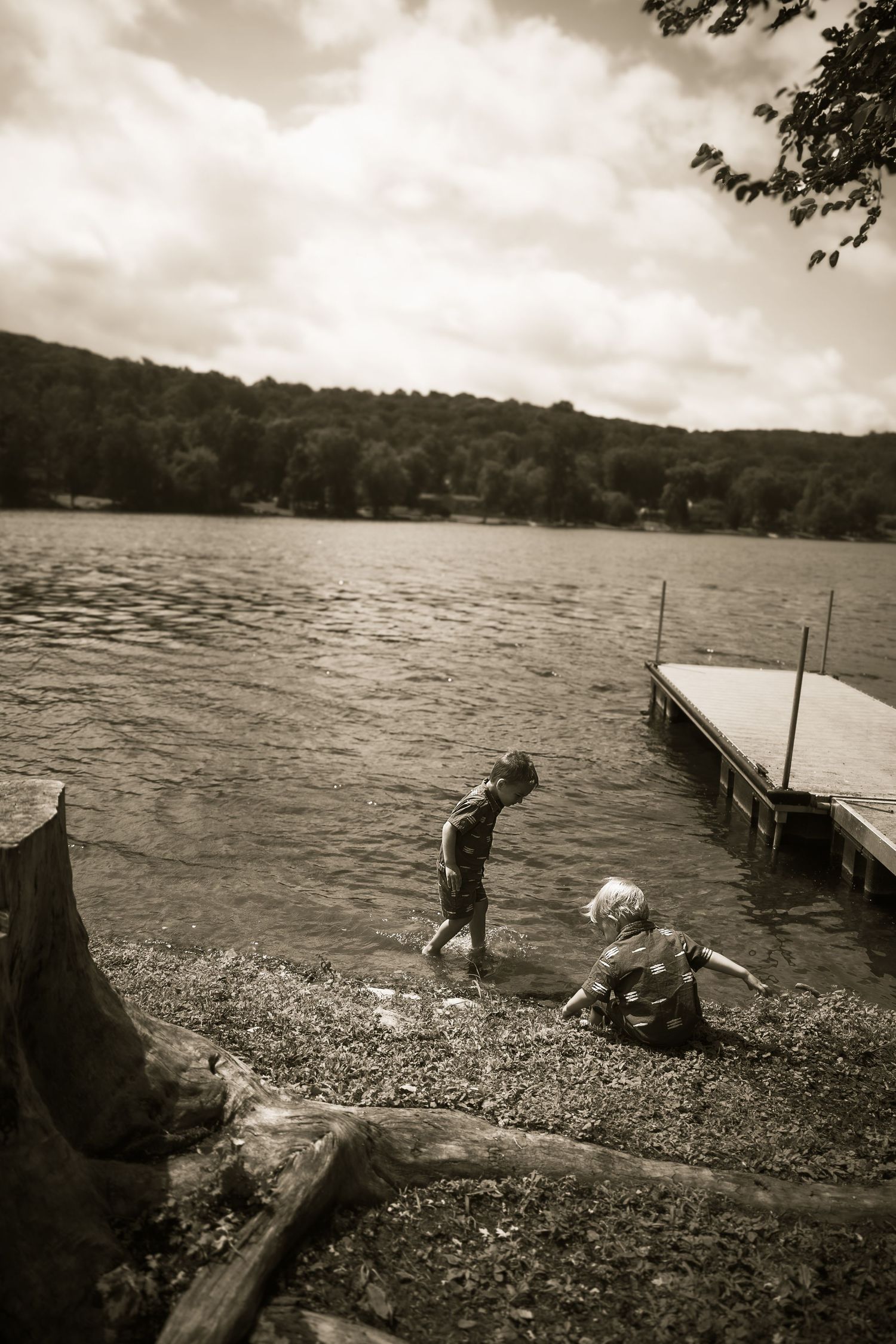 Vintage sepia photograph sequence shows children playing and fishing on a wooden dock by a lake on a cloudy day.