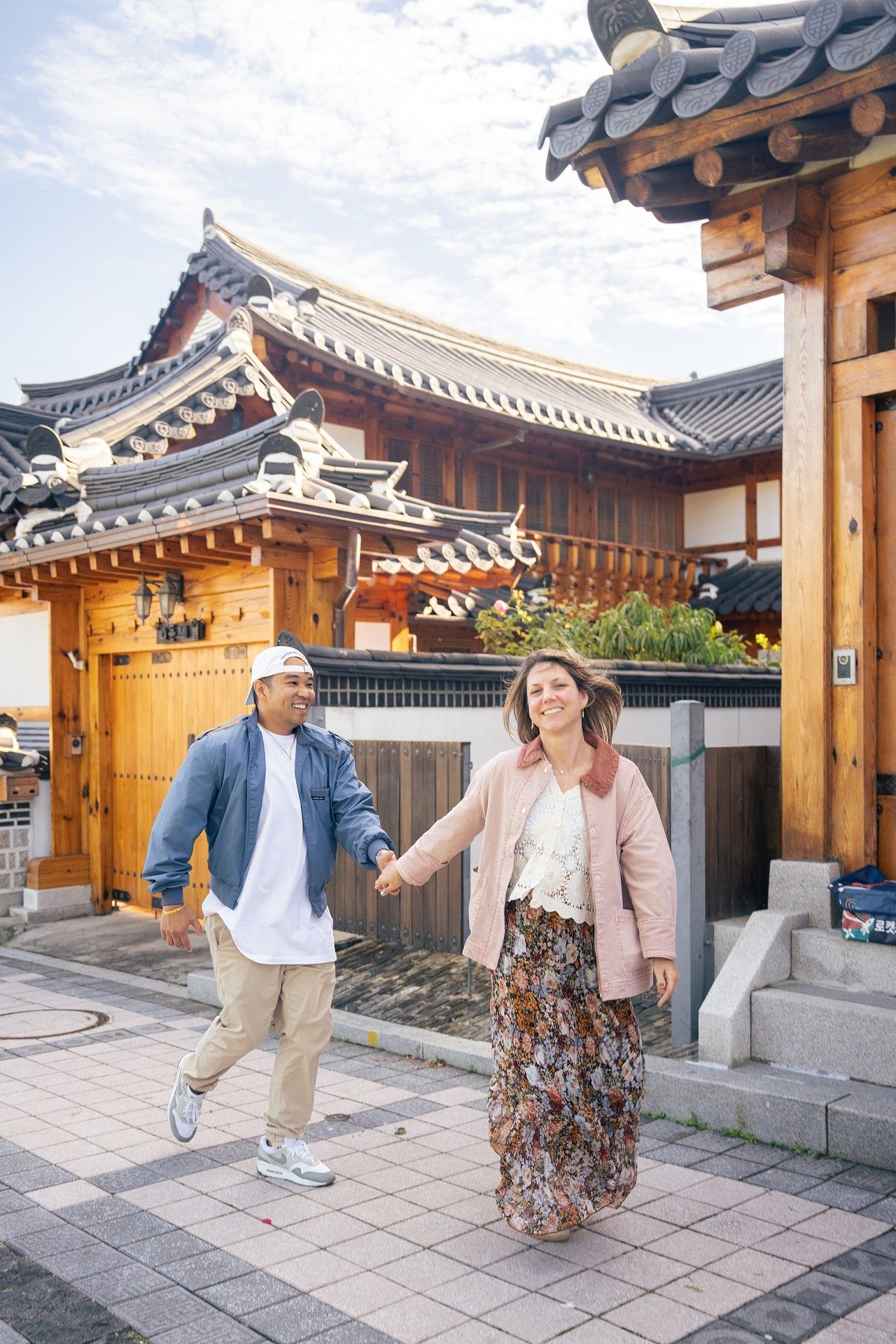 Two people dance together in a traditional Korean hanok courtyard with traditional architecture and tiled roofs.