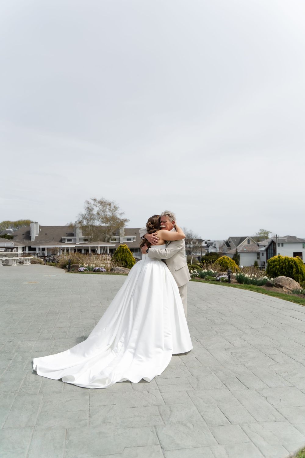 Bride and groom share a romantic embrace outdoors on a stone plaza on their wedding day.