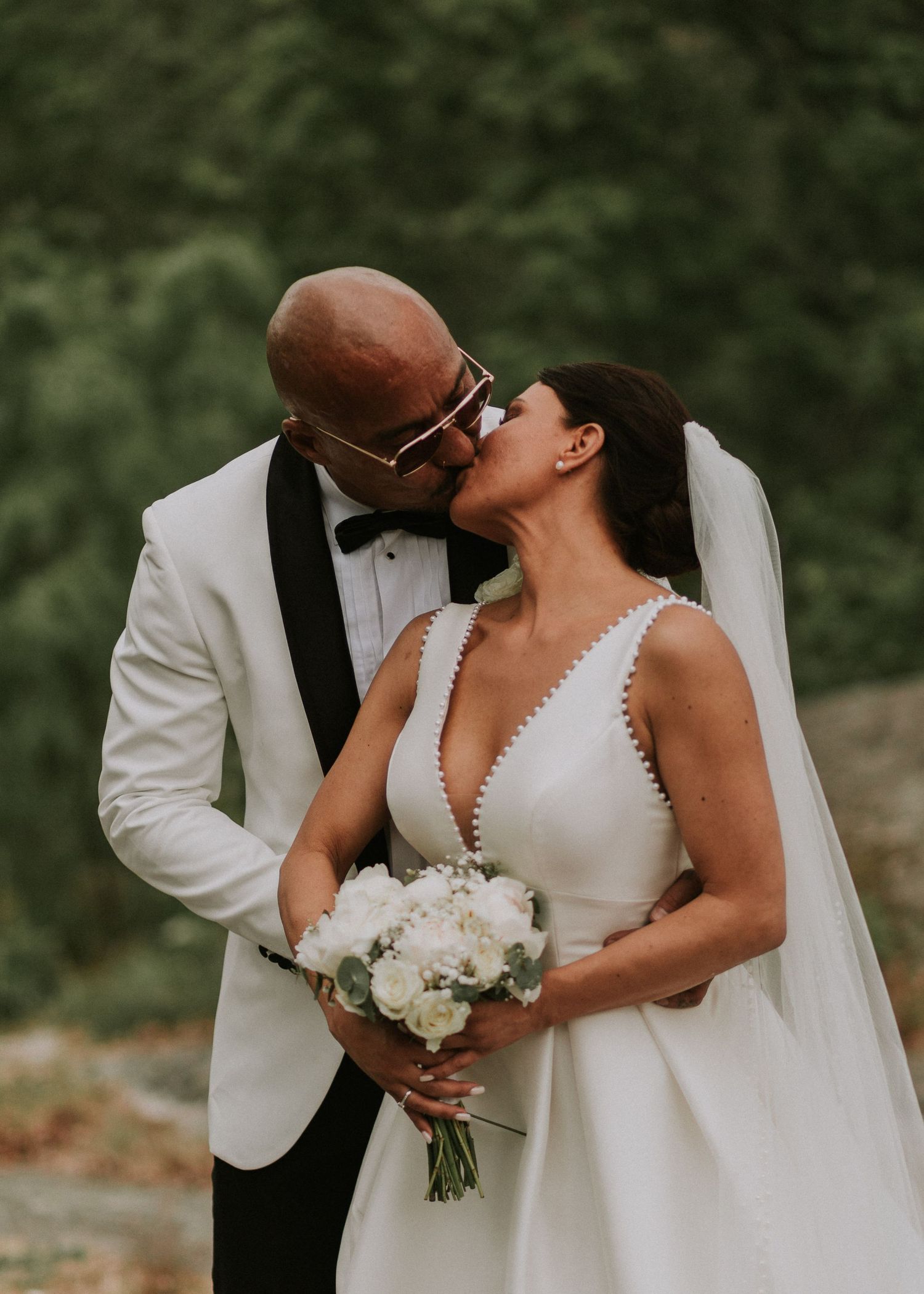 Bride and groom sharing a kiss on their wedding day outdoors.