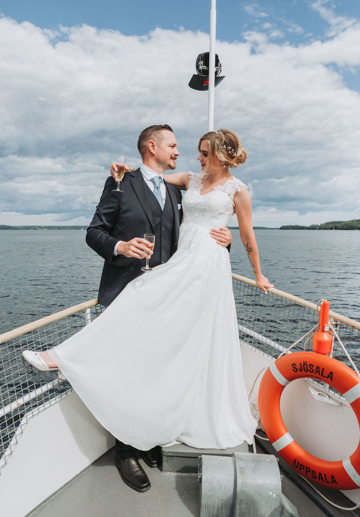 Bride and groom celebrating on a boat deck with champagne on a sunny day.
