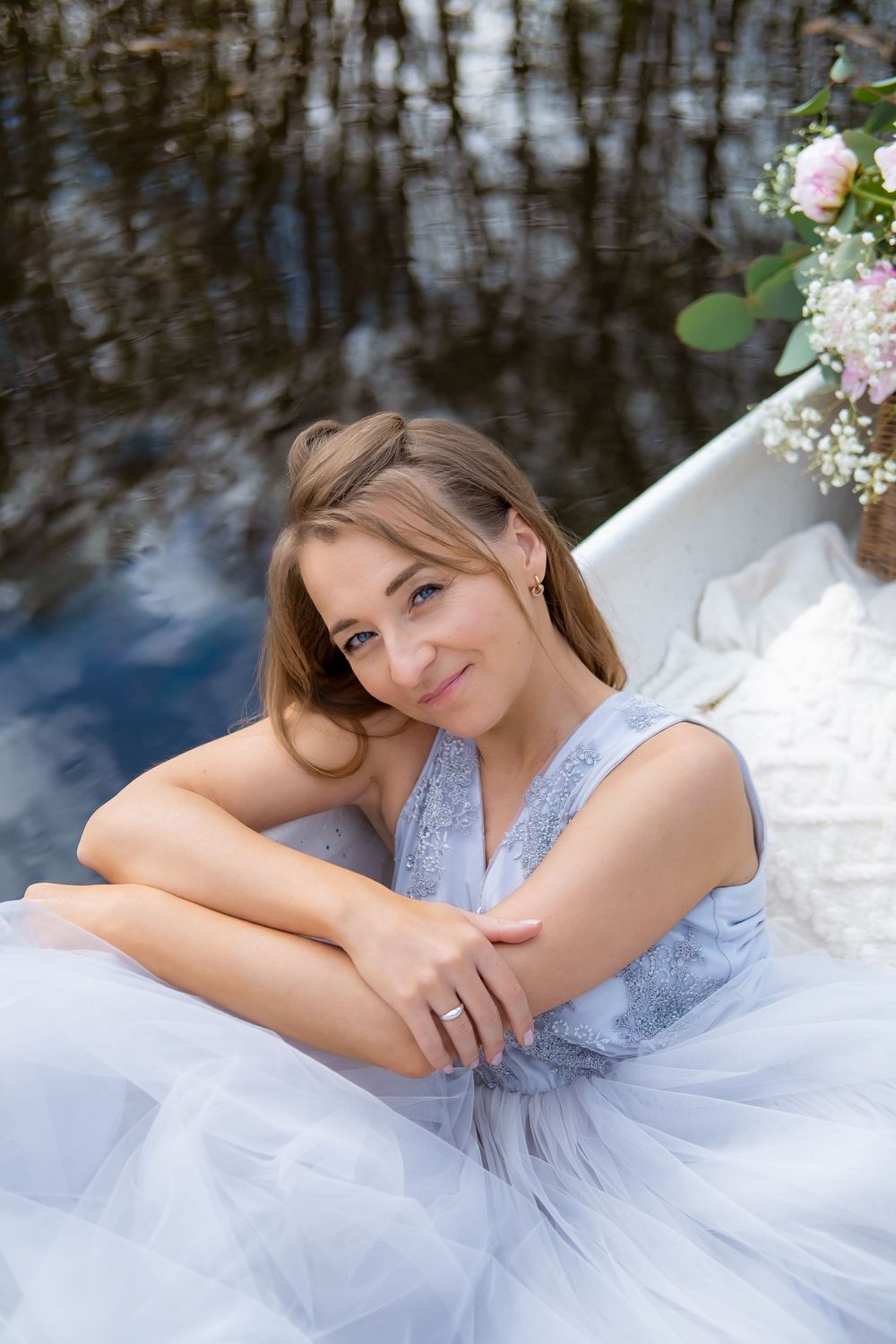 Ethereal portrait series of a person in a flowing white tulle dress and blue top reclining by a reflective pond.