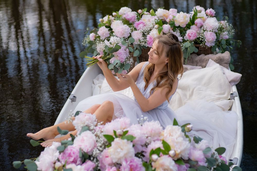 A romantic wedding scene with flowing white dress and pink floral bouquets reflected in dark water.
