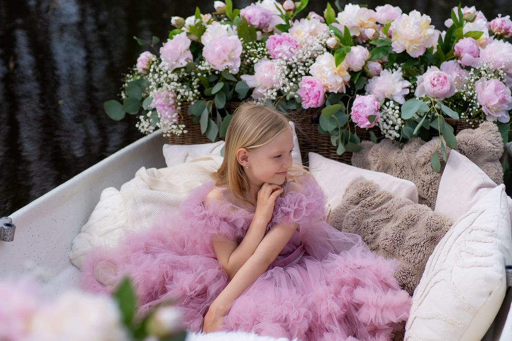 A dreamy portrait session features a pink tulle gown surrounded by delicate pink and white floral arrangements.