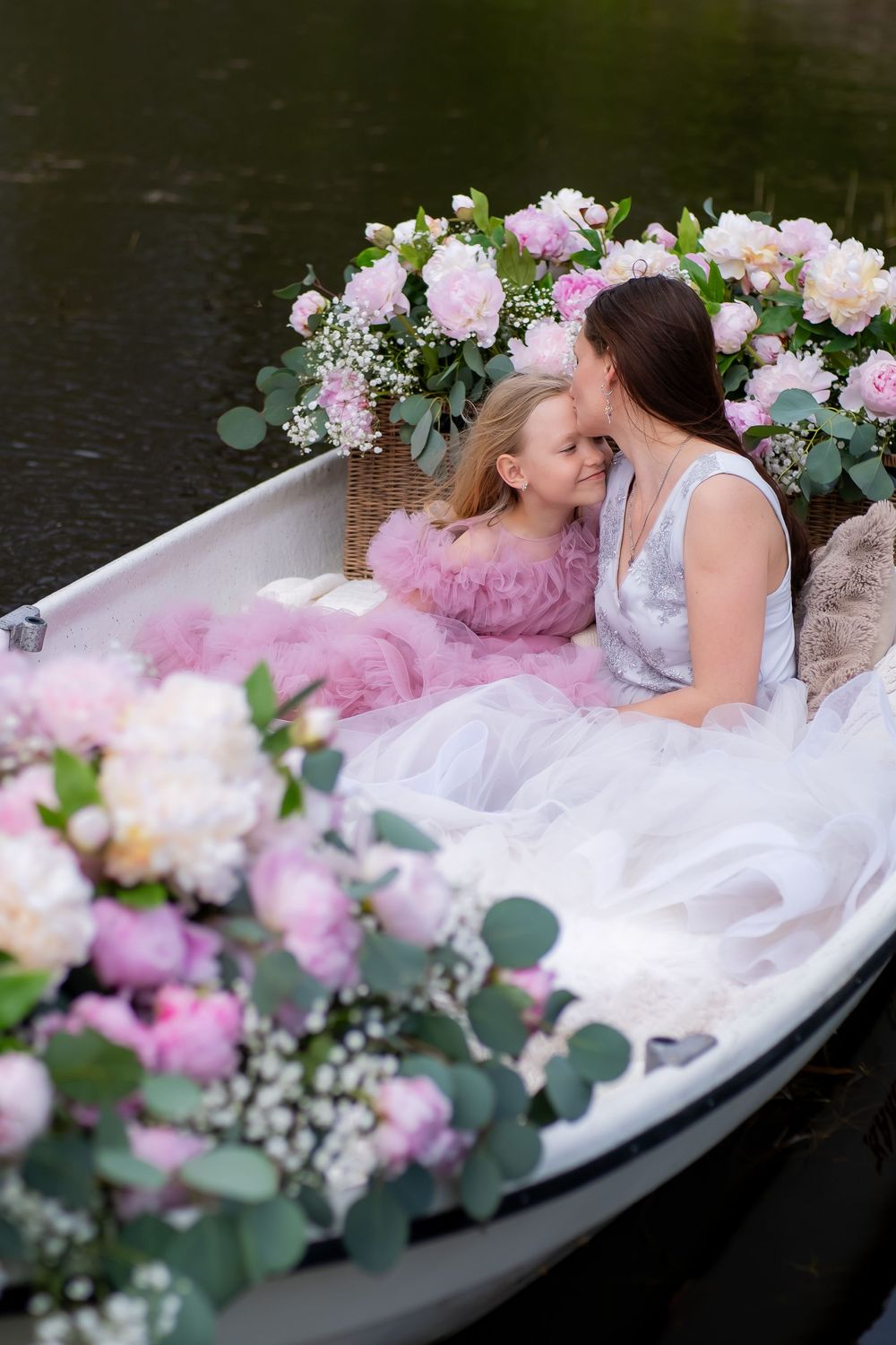 A vintage clawfoot bathtub decorated with pink and white flowers and eucalyptus leaves for a romantic photoshoot.