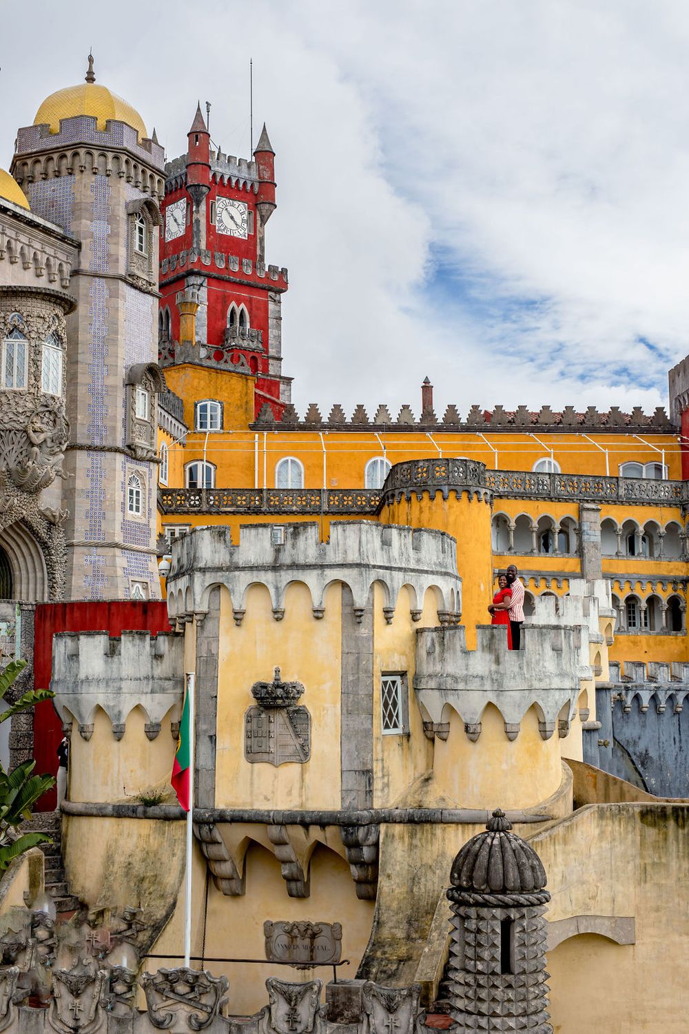 Colorful towers and architectural details of the historic Pena Palace in Sintra, Portugal against a cloudy sky.