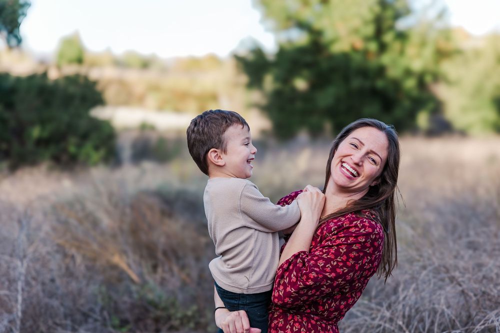 A couple shares joyful moments together while posing outdoors in a natural setting during a photo session.