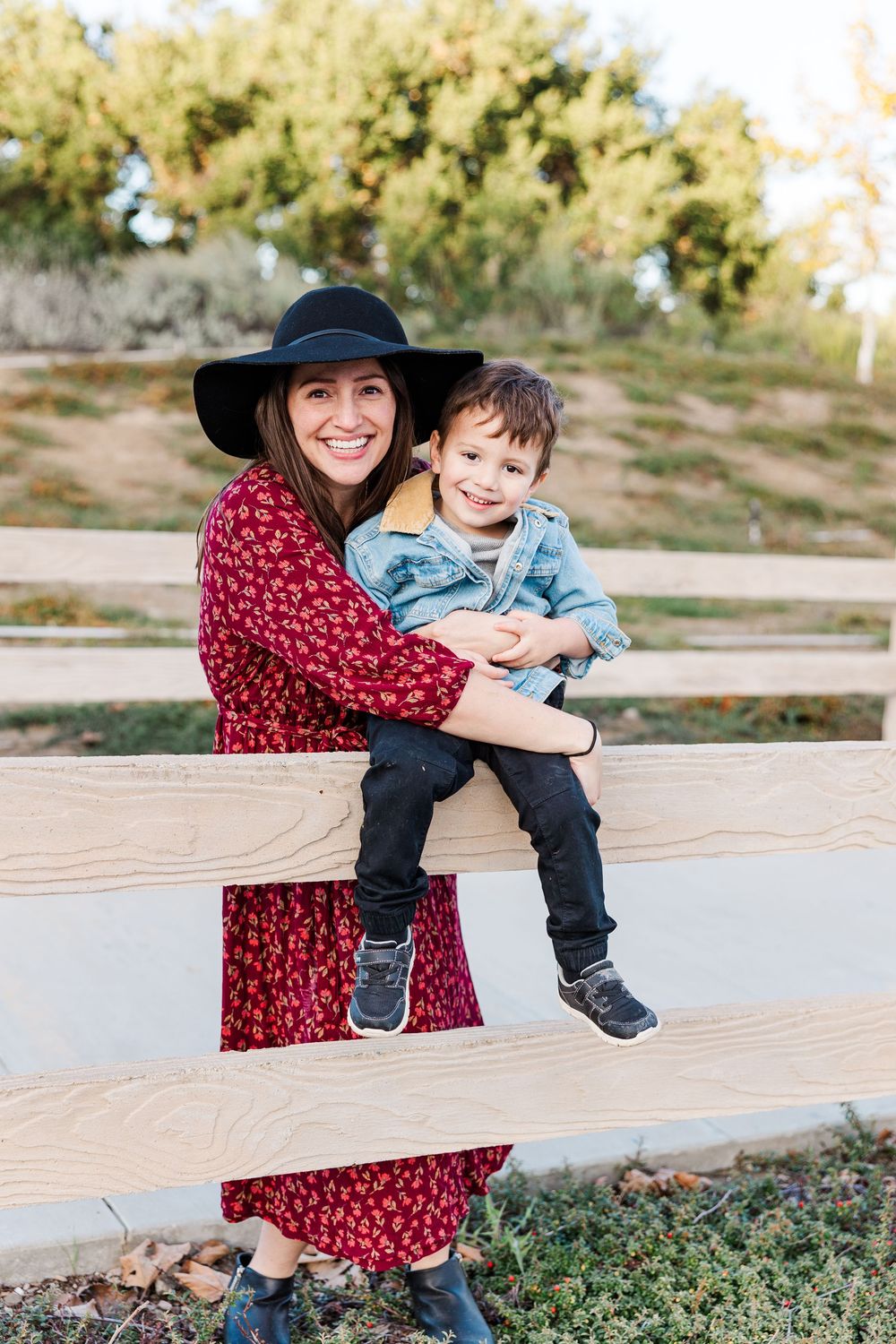 A tender moment shared between parent and child sitting on a wooden bench in an outdoor setting.
