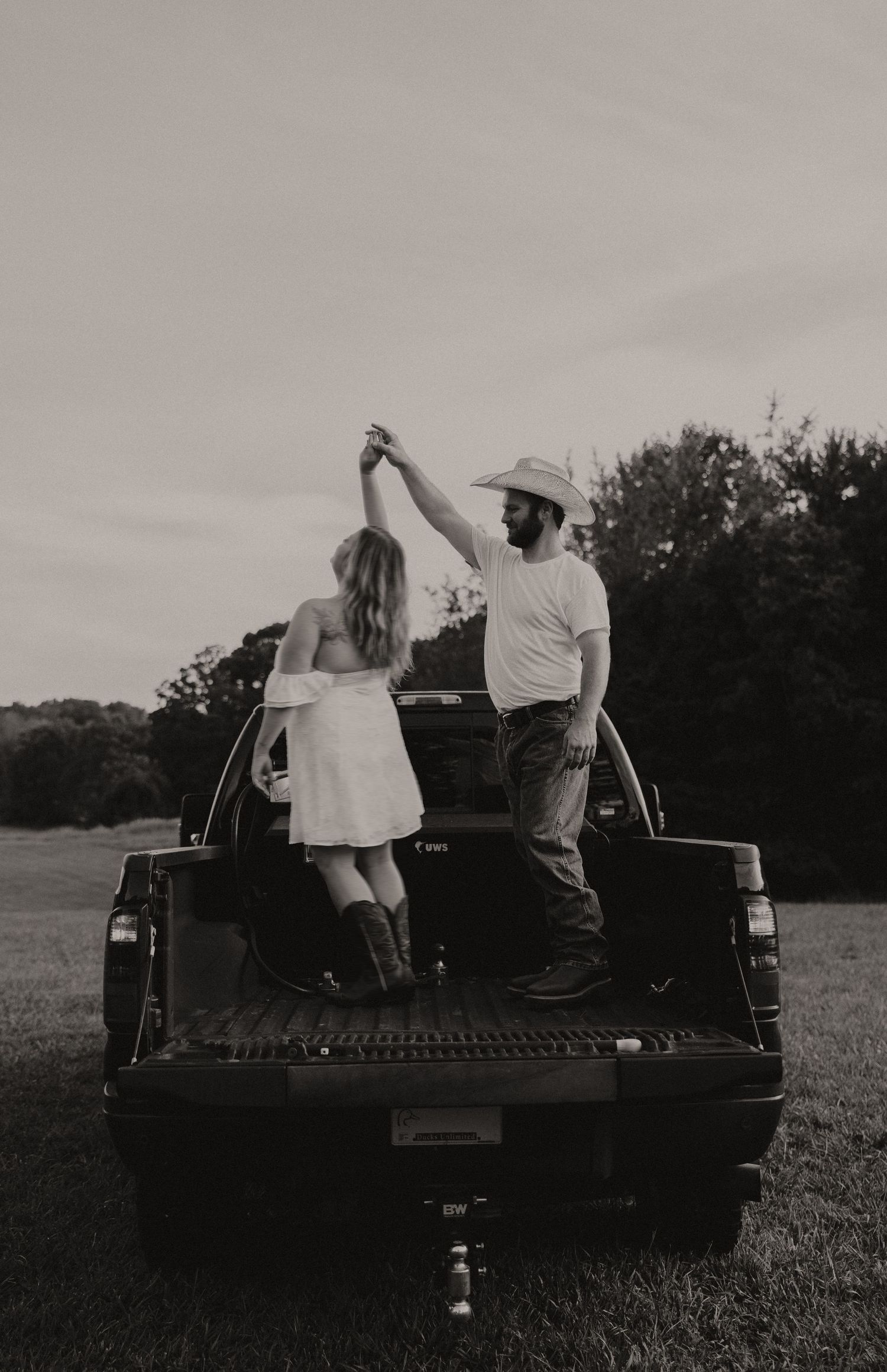 Black and white series of a couple sharing romantic moments on the back of a pickup truck.