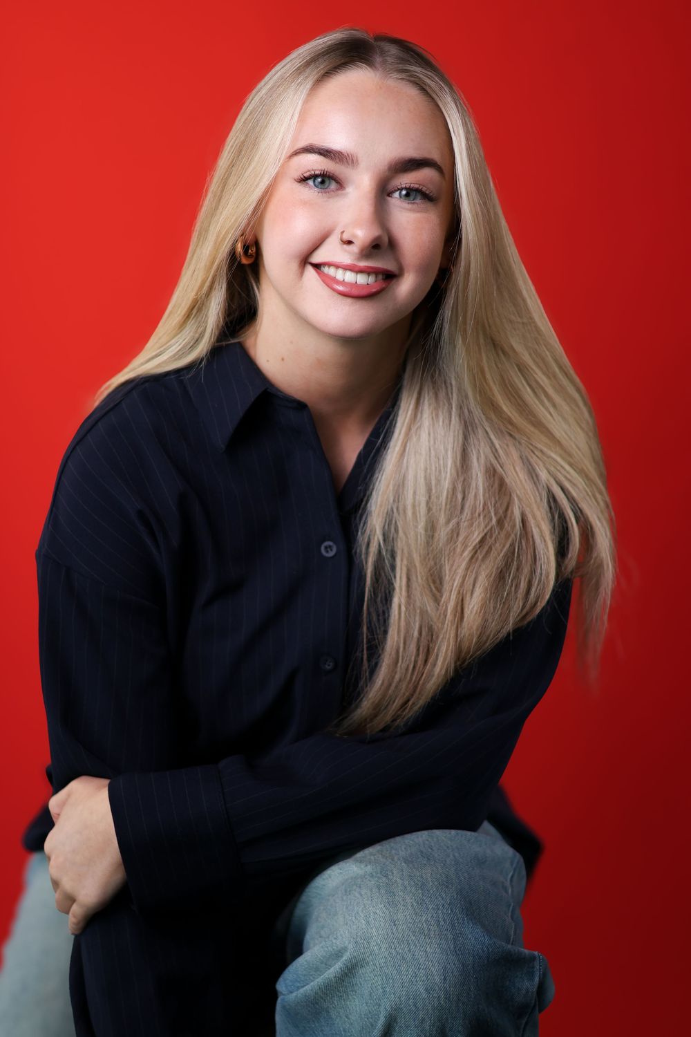 Portrait series against red background showing a person in black sweater with blonde hair in various casual poses.