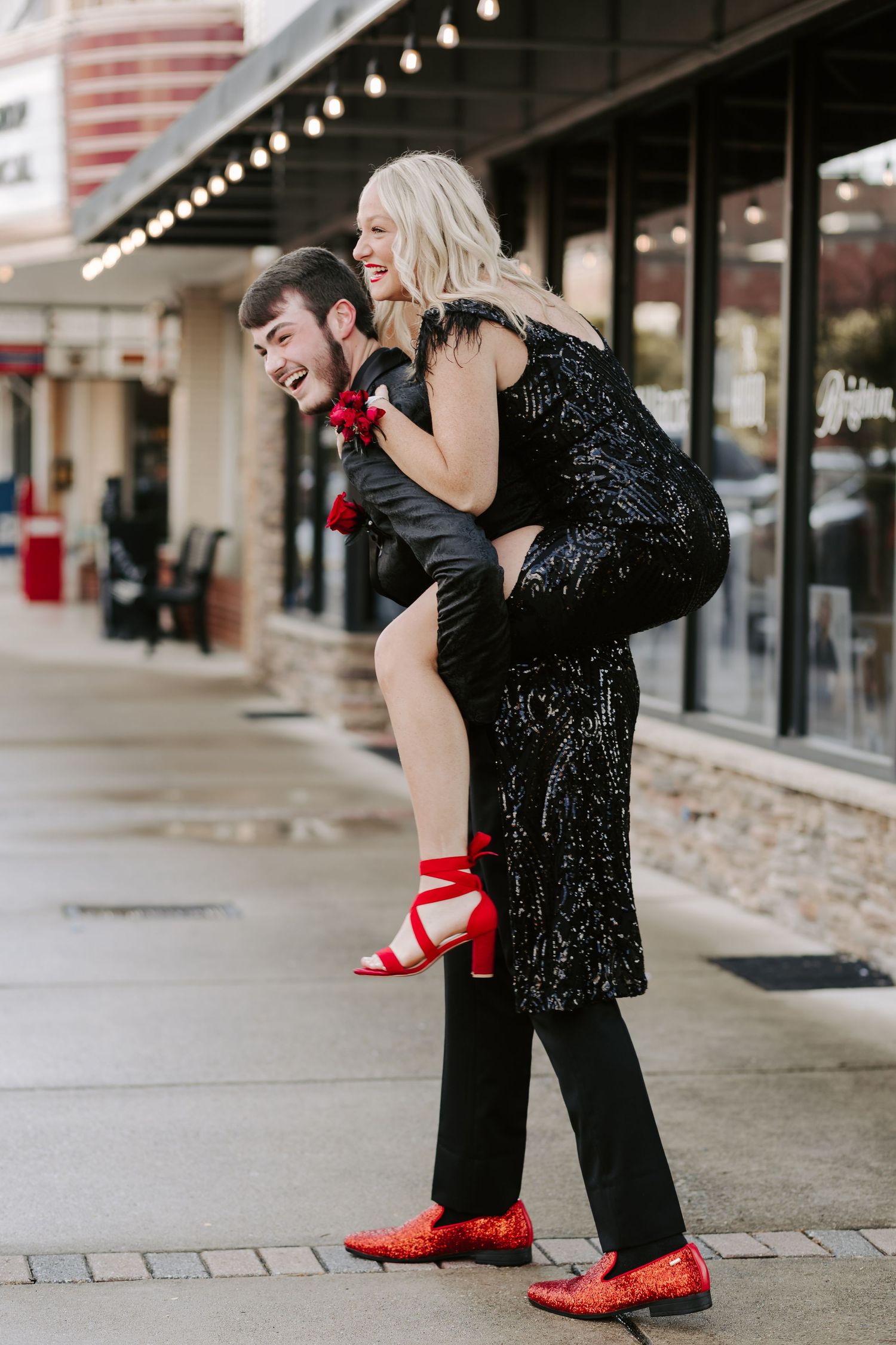 A couple in formal wear shares a romantic dance move outside a shop.