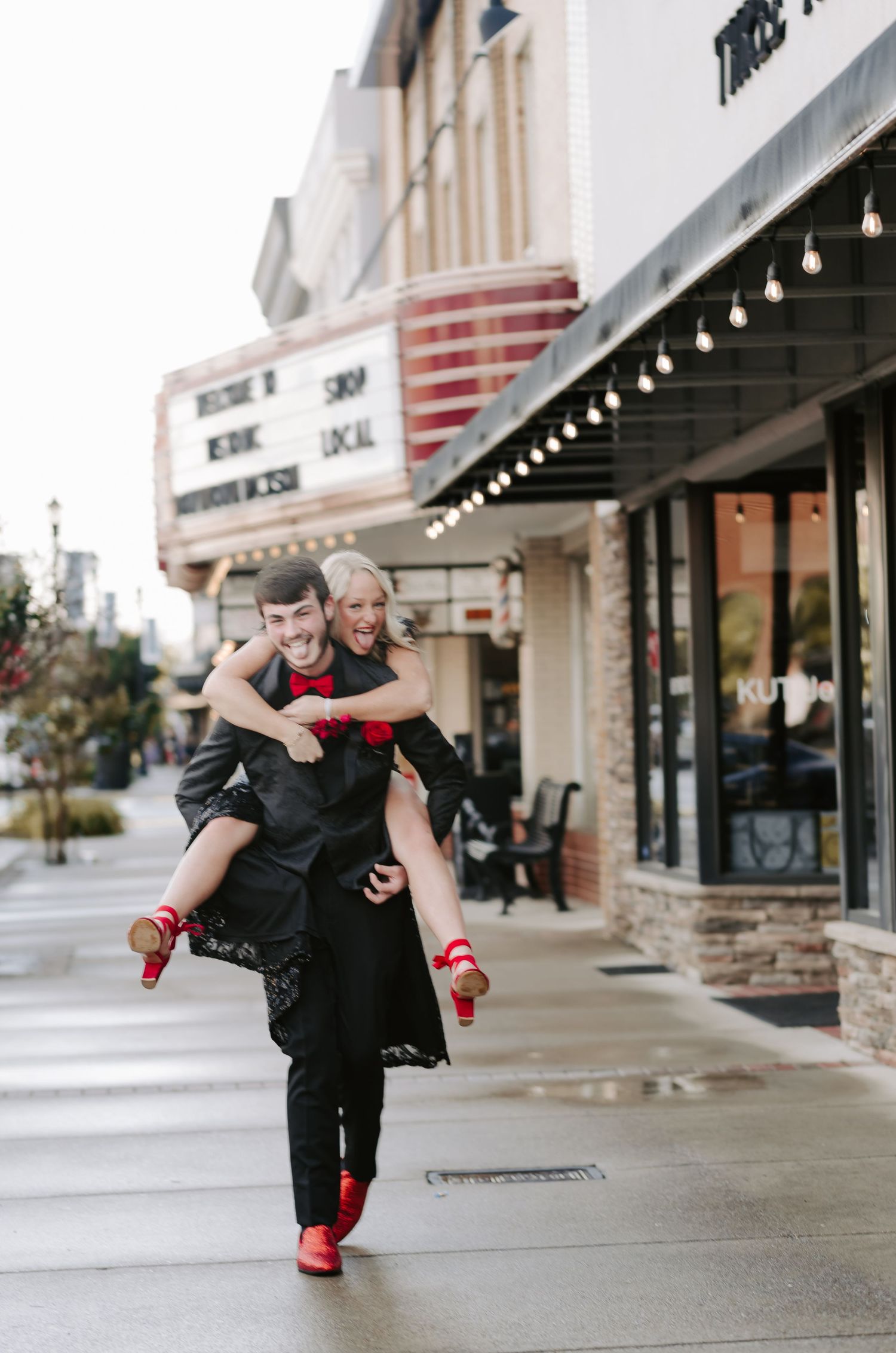A couple dances and poses playfully outside a local storefront.