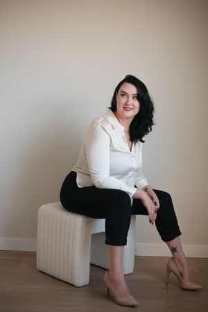 A series of five professional portrait poses showing someone in a white blouse and black pants seated on a light-colored bench.