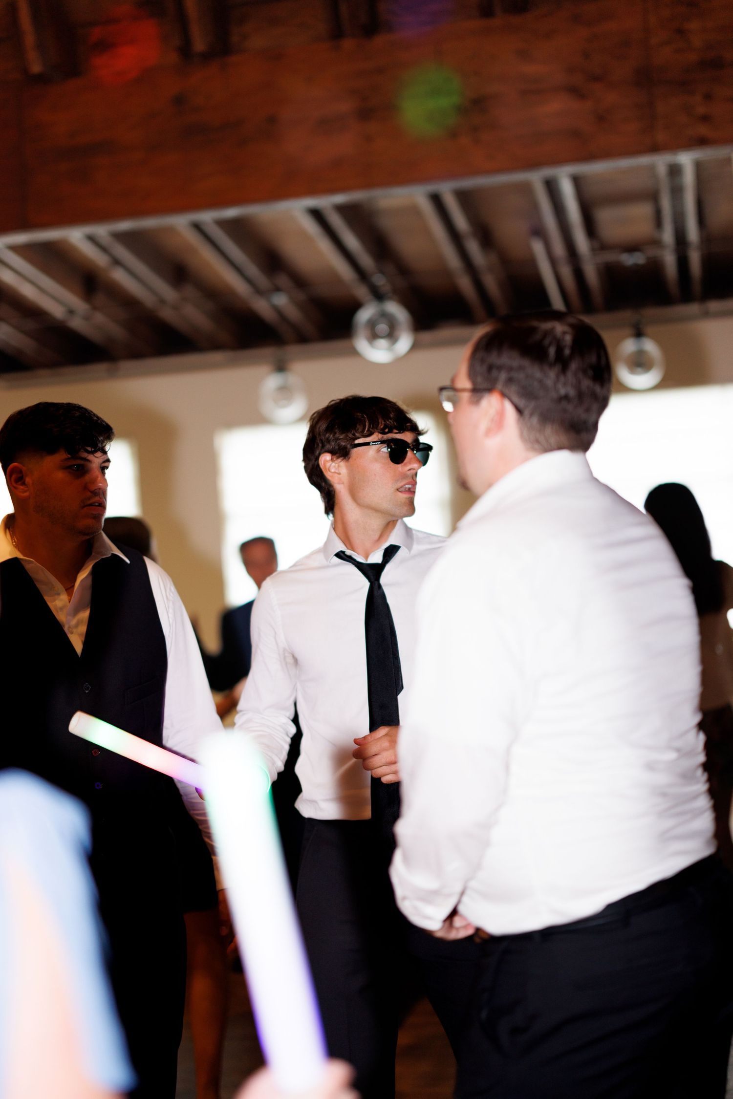 Wedding reception scene with guests in black and white formal attire mingling.