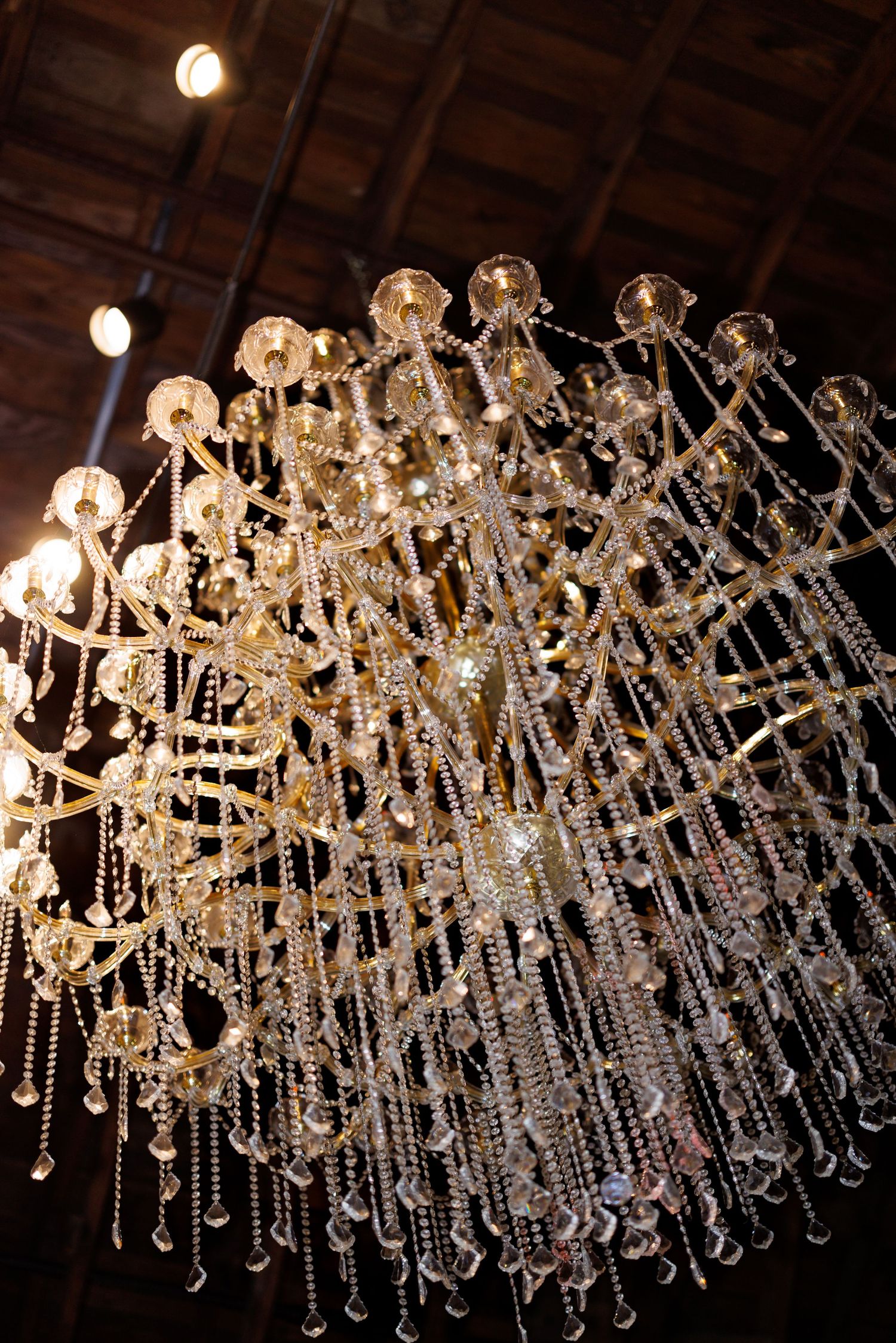 An ornate crystal chandelier with cascading glass beads hangs from a wooden ceiling.