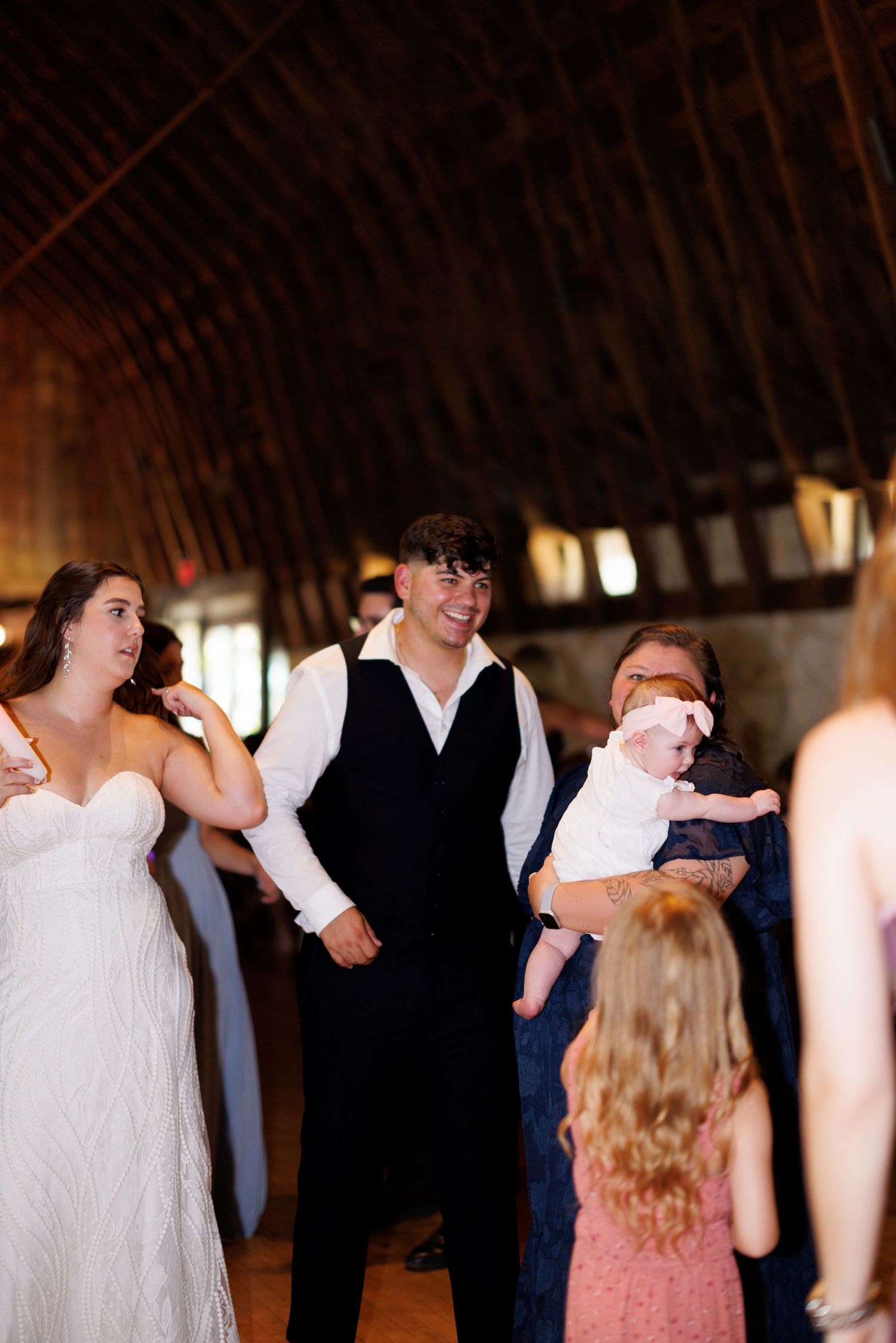 Wedding celebration with guests dancing and laughing in a rustic venue.