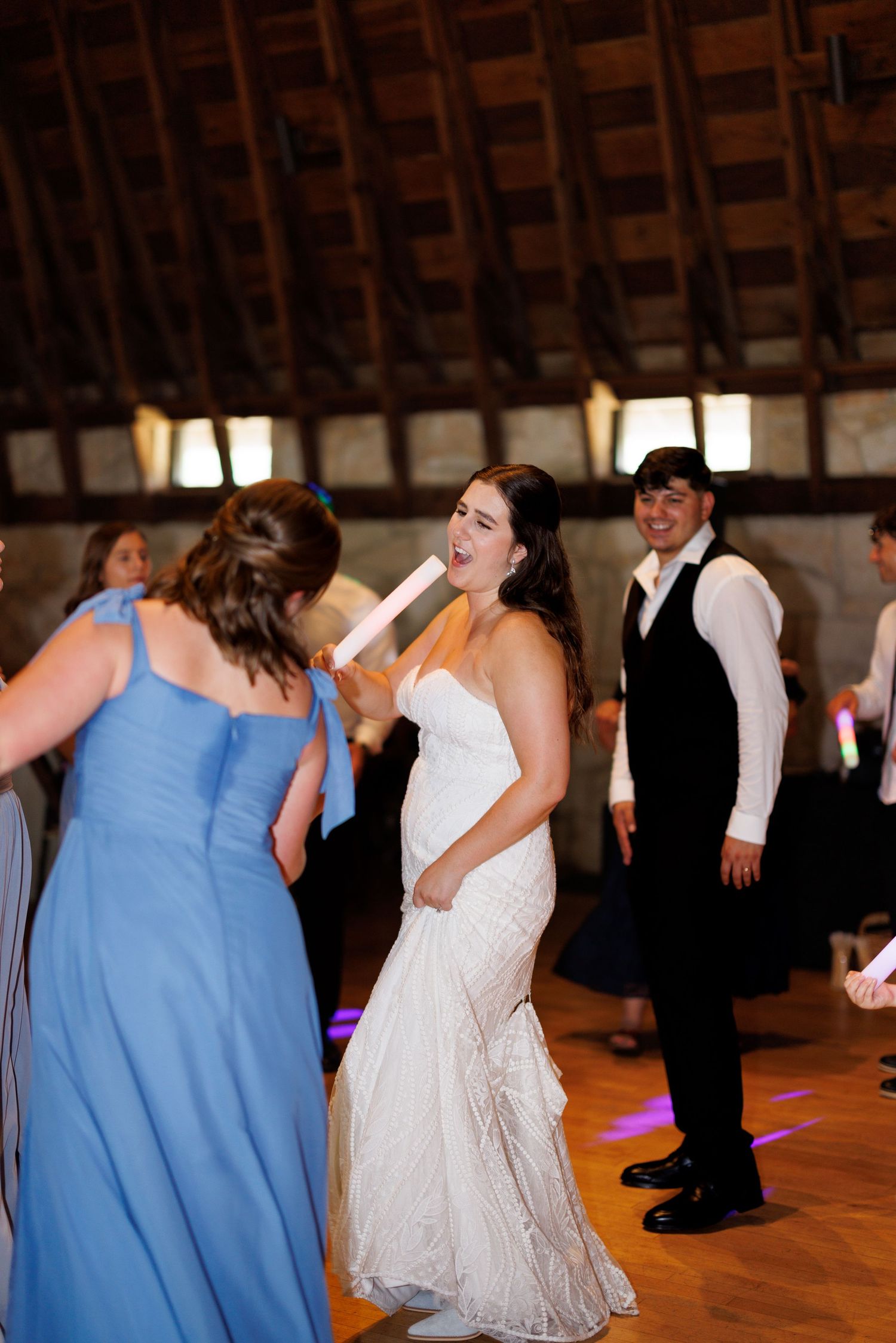Wedding guests dancing and celebrating in a rustic barn venue.